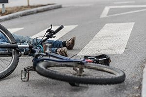 Cropped shot of a wrecked bicycle with the victim’s legs and feet showing. 