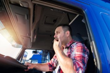 male truck driver behind the wheel yawning