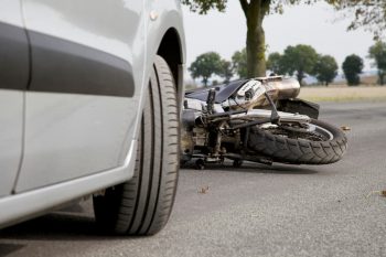A motorcycle in the road after a collision involving a car