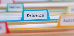 A blurred image of files with the word evidence printed on a blue tab.