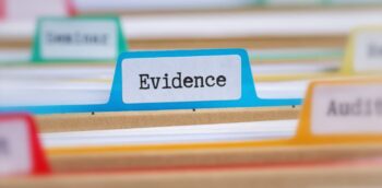 A blurred image of files with the word evidence printed on a blue tab.